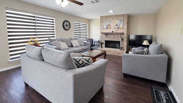 A living room with a fireplace, a ceiling fan, and a flat-screen TV. - Sleeps 8  • w Parking  • Fern Valley Retreat (Houston)