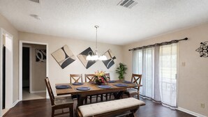A dining room with a wooden table, chairs, a bench, and a hanging light fixture. - Sleeps 8  • w Parking  • Fern Valley Retreat (Houston)