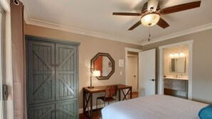 Une chambre à coucher comprenant un lit, un bureau, une chaise, une armoire et un ventilateur de plafond.