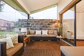 A cozy balcony with a stone wall, wicker furniture, and a view of the cityscape. - Casa do Santo by Homie (Santa Cruz)