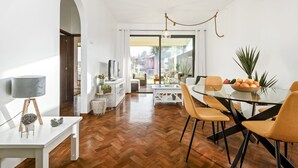 Un espace repas moderne avec une table en verre, des chaises en bois et une vue sur l’extérieur.