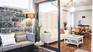 Un salon moderne avec un mur en pierre, un canapé, une table basse et une porte vitrée donnant sur une autre pièce.