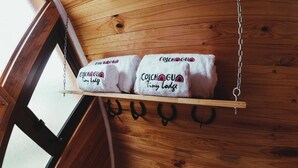 A wooden shelf with towels hanging on hooks, labeled "Colchagui Tiny Lodge." - Colchagua Tiny Lodge (Santa Cruz)