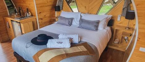 A cozy wooden room with a bed, bedside tables, and a window.