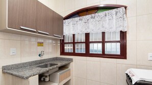 Una cucina con un piano di lavoro in granito, un lavello e una finestra con tenda in pizzo.