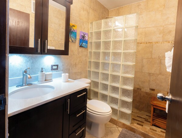 A bathroom with a large mirror, a sink with a modern faucet, a toilet, and a glass shower enclosure.