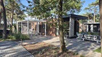 Un patio exterior moderno con zona de estar cubierta, una mesa de picnic y una terraza de madera.
