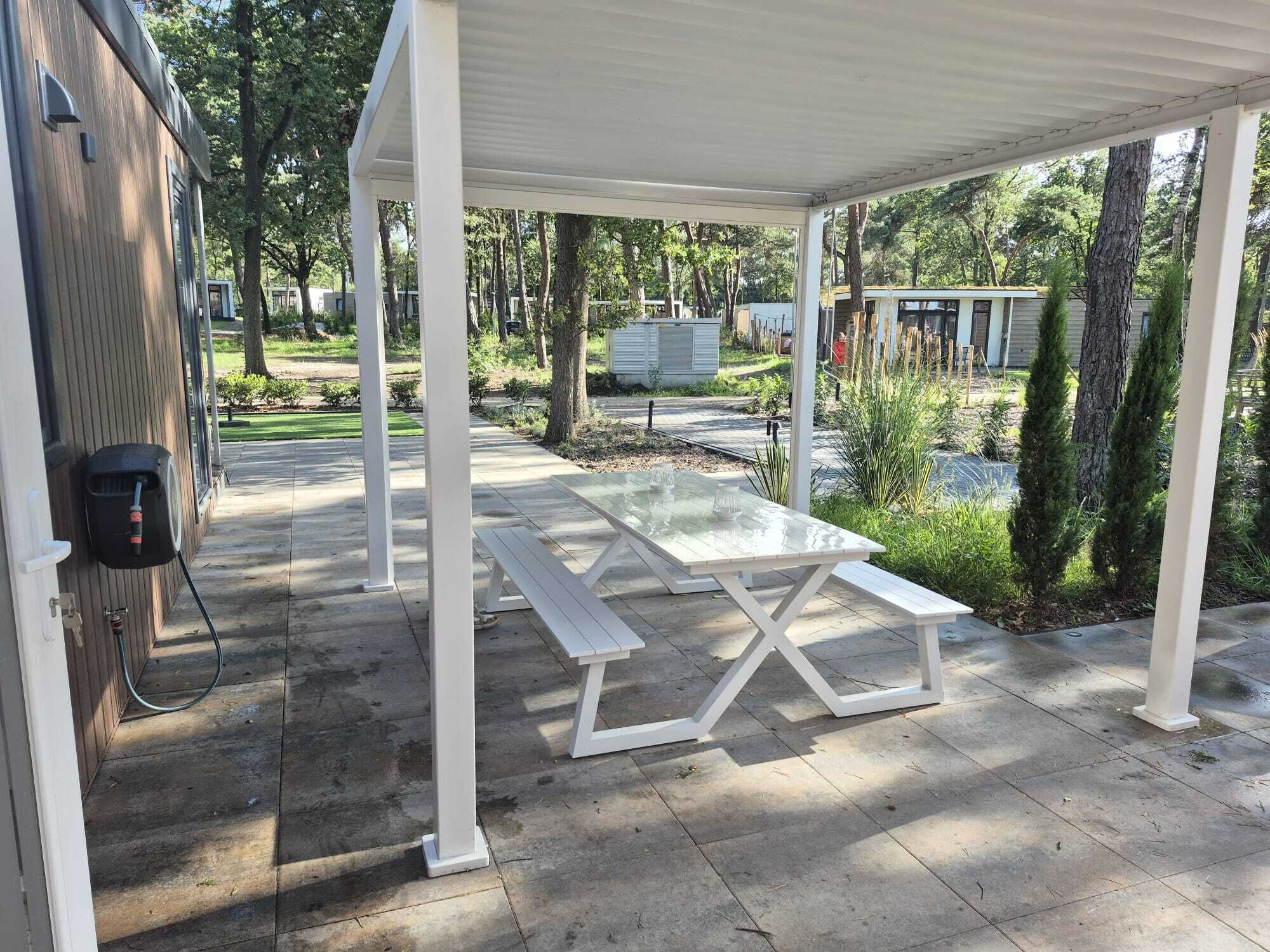 A covered patio area with a picnic table and a hose connected to a building.