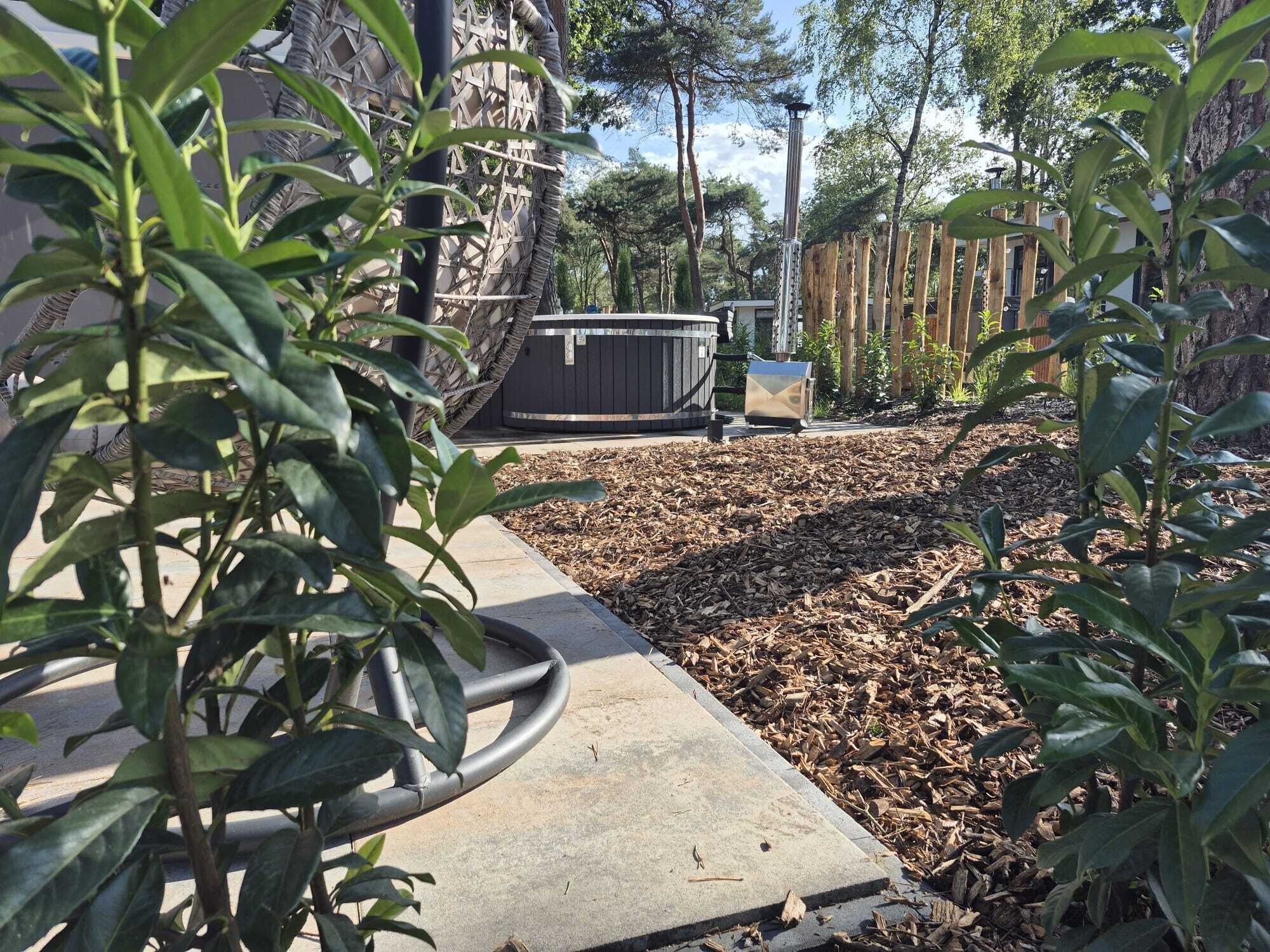 A patio area with a hot tub, wooden deck, and surrounding greenery.