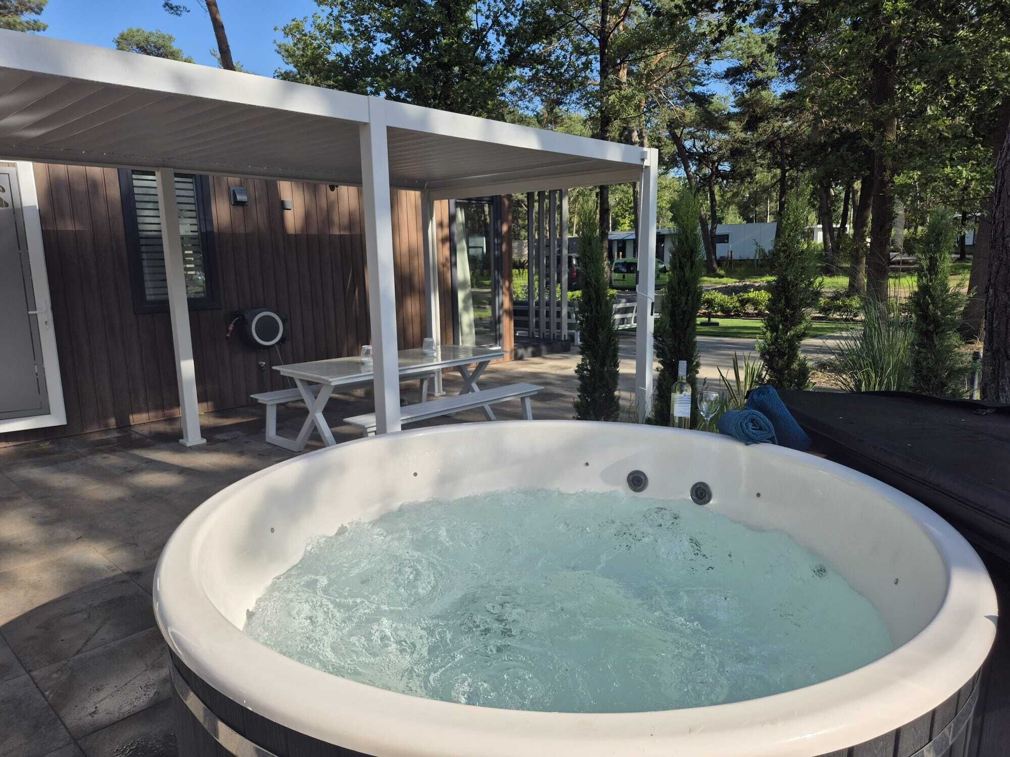 Ein Whirlpool in einem überdachten Außenbereich mit Holzterrasse und Picknicktisch.