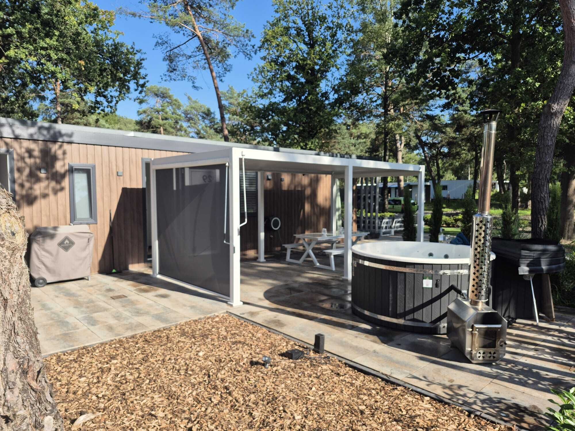 Un patio couvert avec un jacuzzi, des sièges d’extérieur et un barbecue.