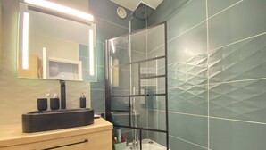 A modern bathroom with a large mirror, a black sink, and a glass-enclosed shower. - 06CO : beautiful apartment at the foot of the slopes with balcony (Guillaumes)