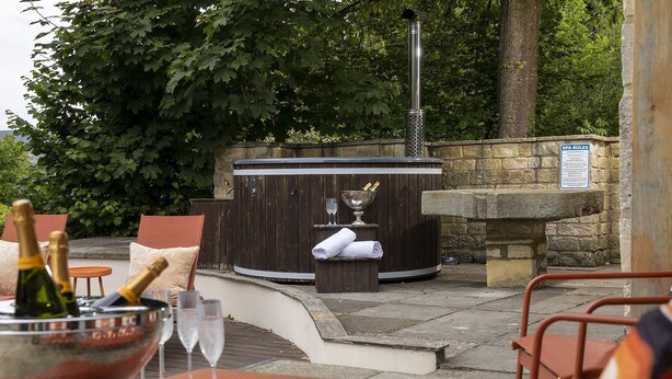Un área de spa con un jacuzzi, asientos y una pared de piedra.