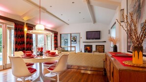 Un comedor moderno con una mesa redonda, sillas blancas y detalles en rojo.