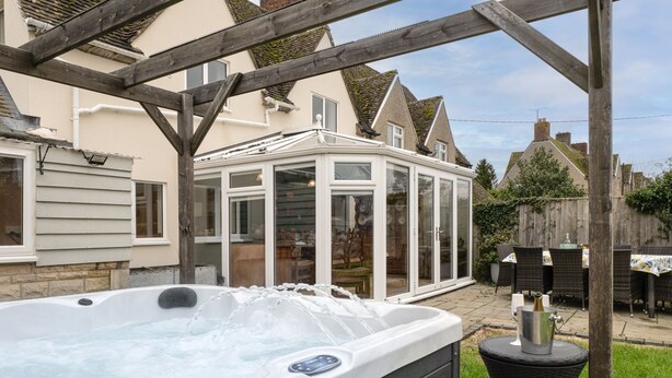 Ein Whirlpool in einem überdachten Außenbereich mit einer hölzernen Pergola darüber.