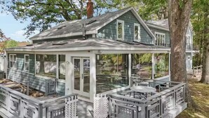A house with a covered porch, a fenced deck, and a pond.