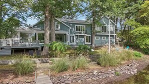 A two-story house with a deck and a pond.