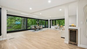 A spacious living area with large windows, a dining set, and a fireplace.
