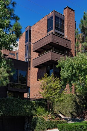 Un edificio moderno de varios pisos con fachada de ladrillo, ventanas amplias y balcones.