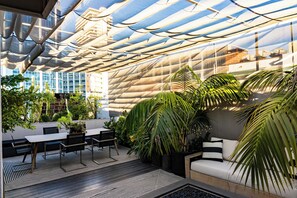 Un jardín interior con una mesa, sillas, un sofá y diversas plantas.