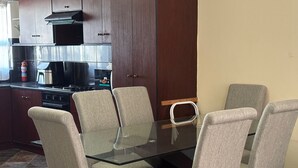 Una cocina moderna con una mesa de vidrio para comer rodeada de seis sillas, una estufa y un microondas.