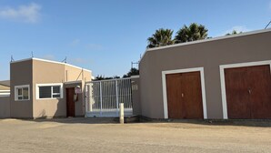 Un edificio con dos grandes puertas de garaje de madera, una entrada porticada y un cielo despejado.