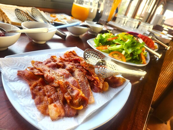 A breakfast table with bacon, a salad, and a glass of orange juice. - Sunny Shore Resort (Phu Quoc)
