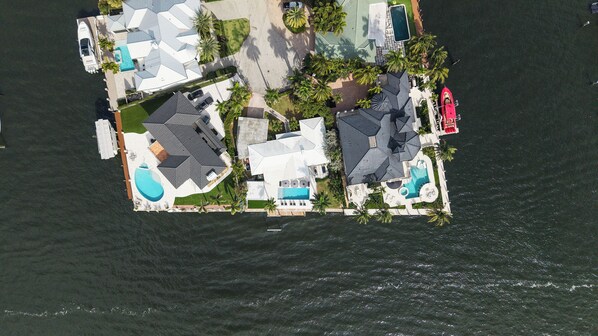 An aerial view of a resort island with multiple pools, a marina, and palm trees.