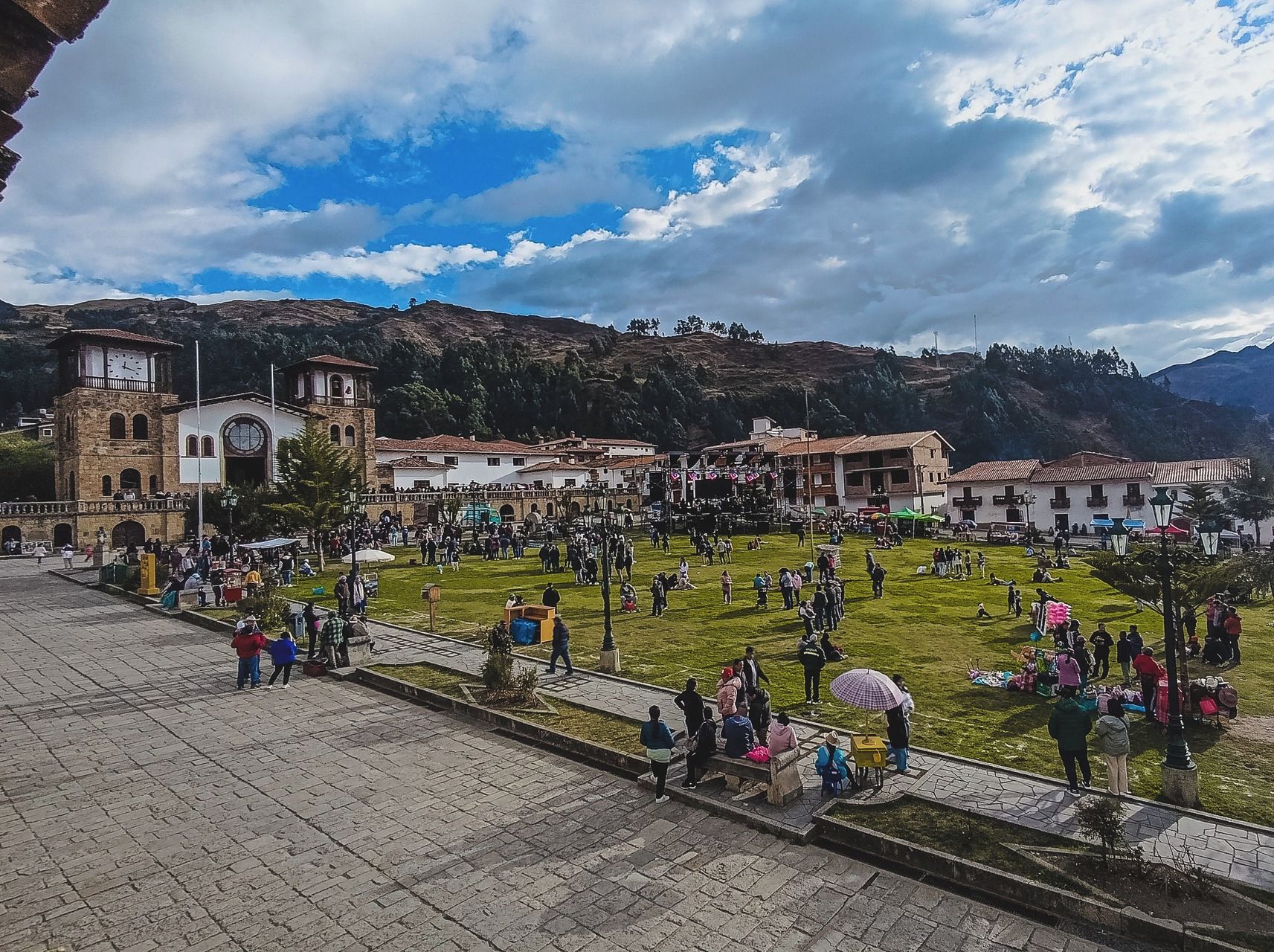 A plaza with stone paving, a clock tower, and buildings with traditional architecture.