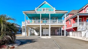 A two-story building with a balcony on the second floor, a covered entrance, and a clear sky.