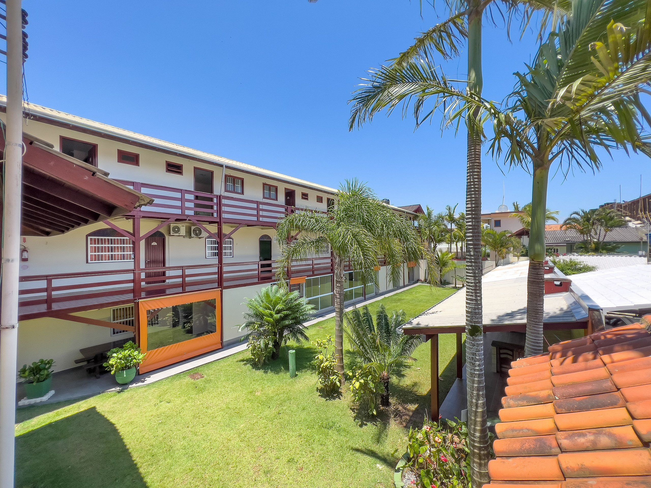 A multi-story building with a balcony, a well-maintained lawn, and several palm trees.