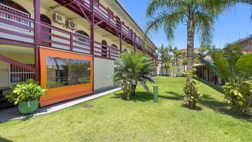 A hotel with a covered outdoor area, a well-maintained lawn, and several palm trees.