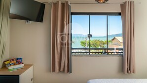 A hotel room with a large window, a flat-screen TV, and a small table with snacks.