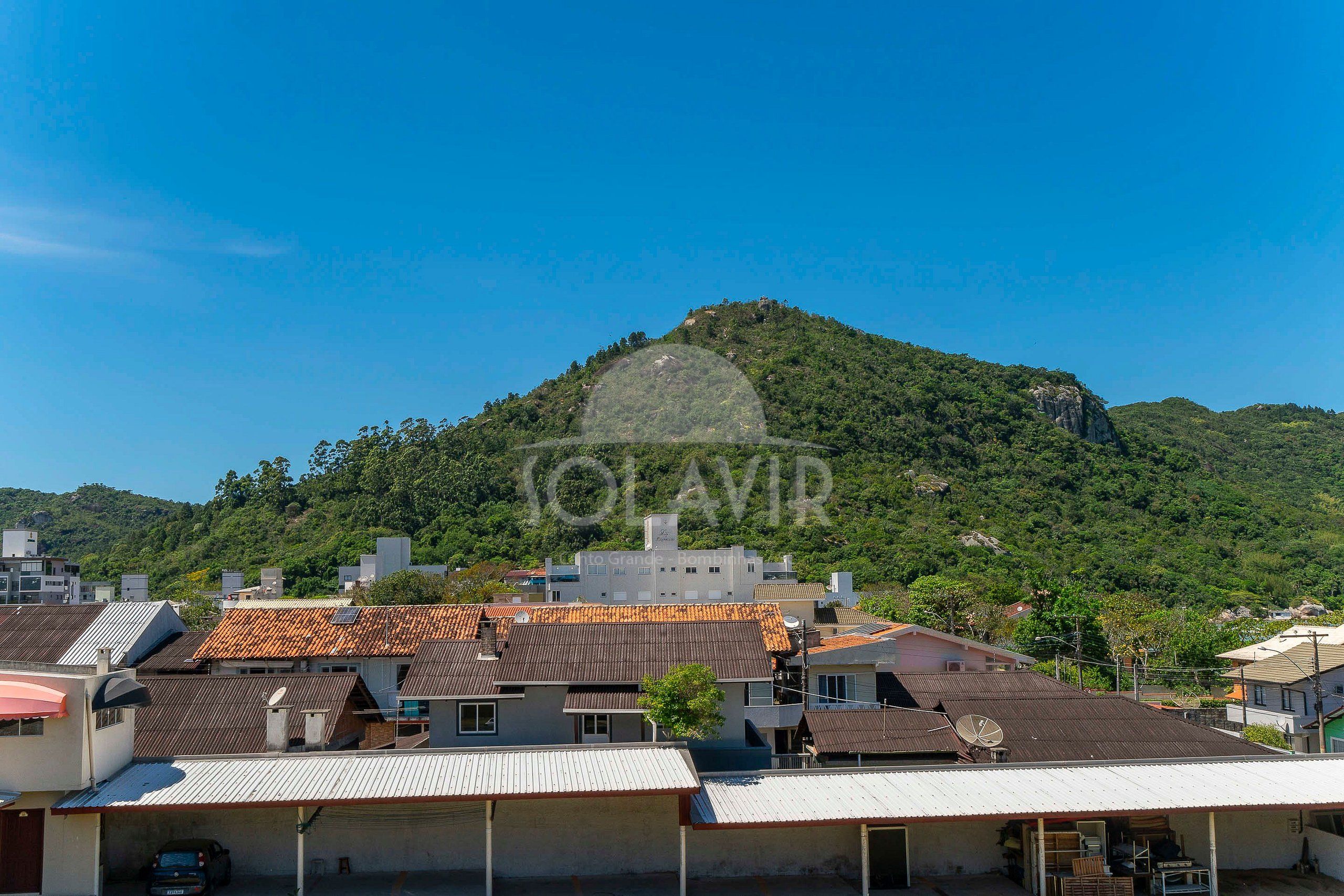 Zona residencial con casas, algunas con paneles solares, y una colina con afloramientos rocosos al fondo.