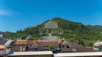 Zona residencial con casas, algunas con paneles solares, y una colina con afloramientos rocosos al fondo.