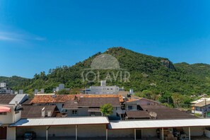 A residential area with houses, some with solar panels, and a hill with a rocky outcrop in the background. - Suíte 1 Ala pôr sol Residencial Solavir (Bombinhas)