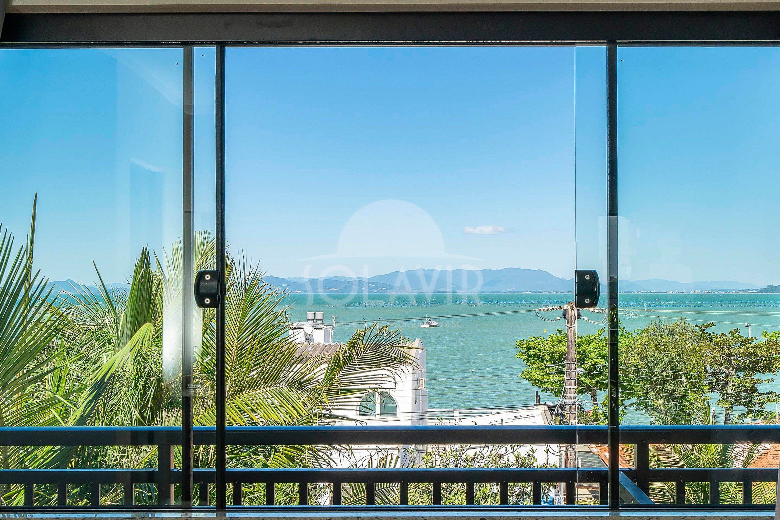 A view from a balcony with a clear sky, a body of water, and a distant mountain range.