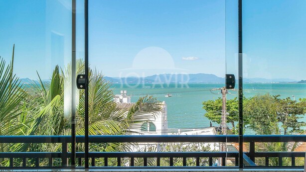 A view from a balcony with a clear sky, a body of water, and a distant mountain range.