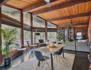 Una habitación amplia con un gran techo de madera, una chimenea de piedra y un comedor con mobiliario moderno.