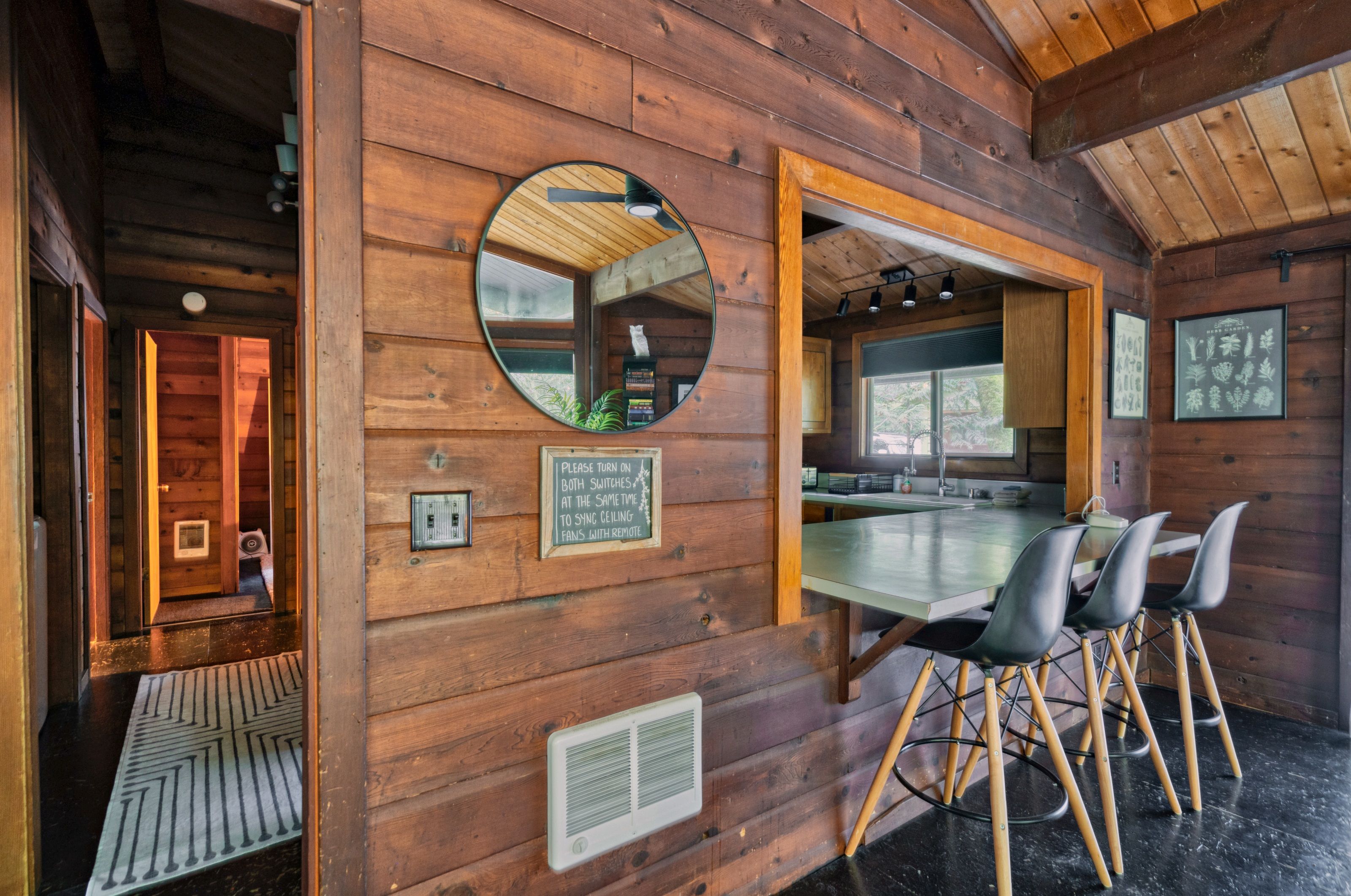 A wooden interior with a dining area, a mirror, and a sign instructing to turn on both switches to sync ceiling fans with remote.