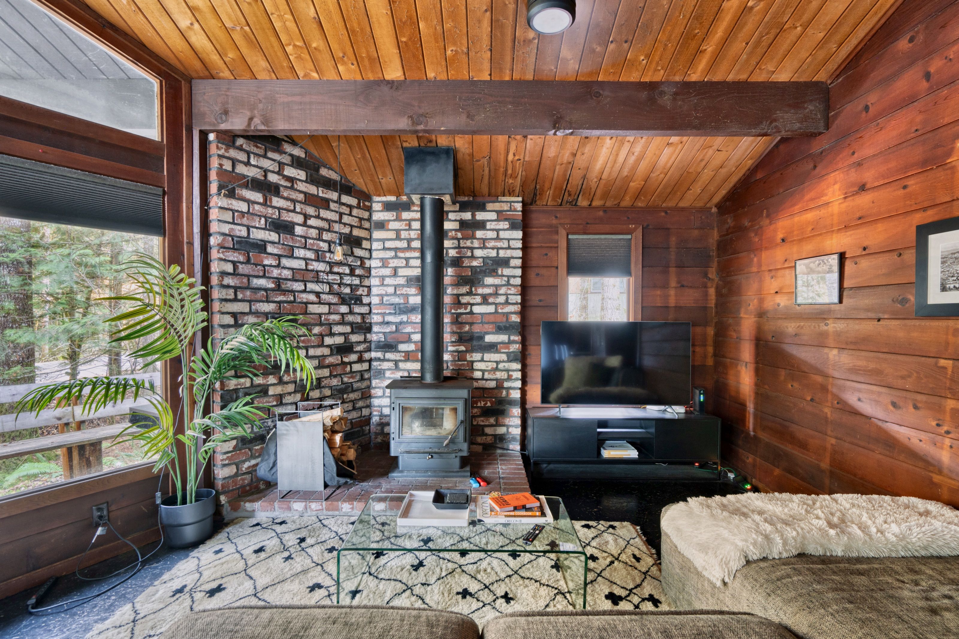 A cozy living room with a brick wall, a fireplace, a television, and a sofa.