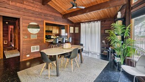 Een houten interieur met een eethoek, keuken en een groot raam.