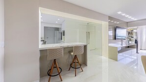 A modern bathroom with a large mirror, a vanity with a white countertop, and two stools. - PASÁRGADA PONTA VERDE, WONDERFUL APARTMENT, CLOSE TO THE BEACH AND WITH SEA VIEW. (Ponta Verde Maceió)