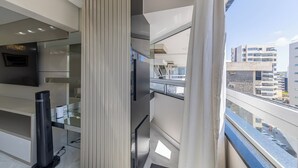 A modern interior with a glass staircase, a flat-screen TV, and a view of the cityscape. - PASÁRGADA PONTA VERDE, WONDERFUL APARTMENT, CLOSE TO THE BEACH AND WITH SEA VIEW. (Ponta Verde Maceió)
