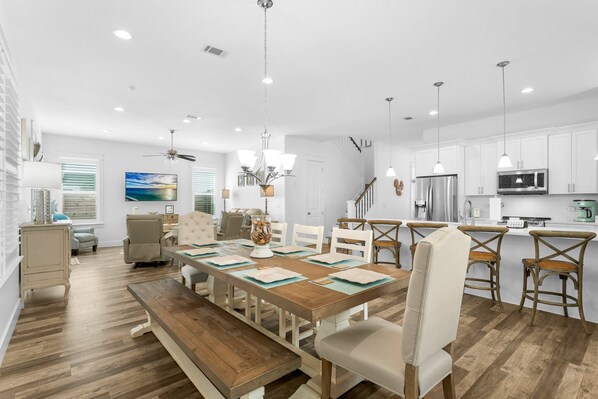 Una cocina moderna con armarios blancos, electrodomésticos de acero inoxidable e iluminación colgante.