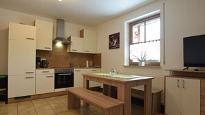 A modern kitchen with white cabinets, a wooden table, and a bench. There is a window with a view of the outside.