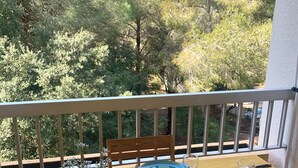 Une table de balcon dressée avec des assiettes bleues, des couverts et une variété de collations et de boissons.