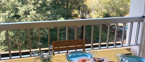 A balcony table set with blue plates, cutlery, and a variety of snacks and drinks.