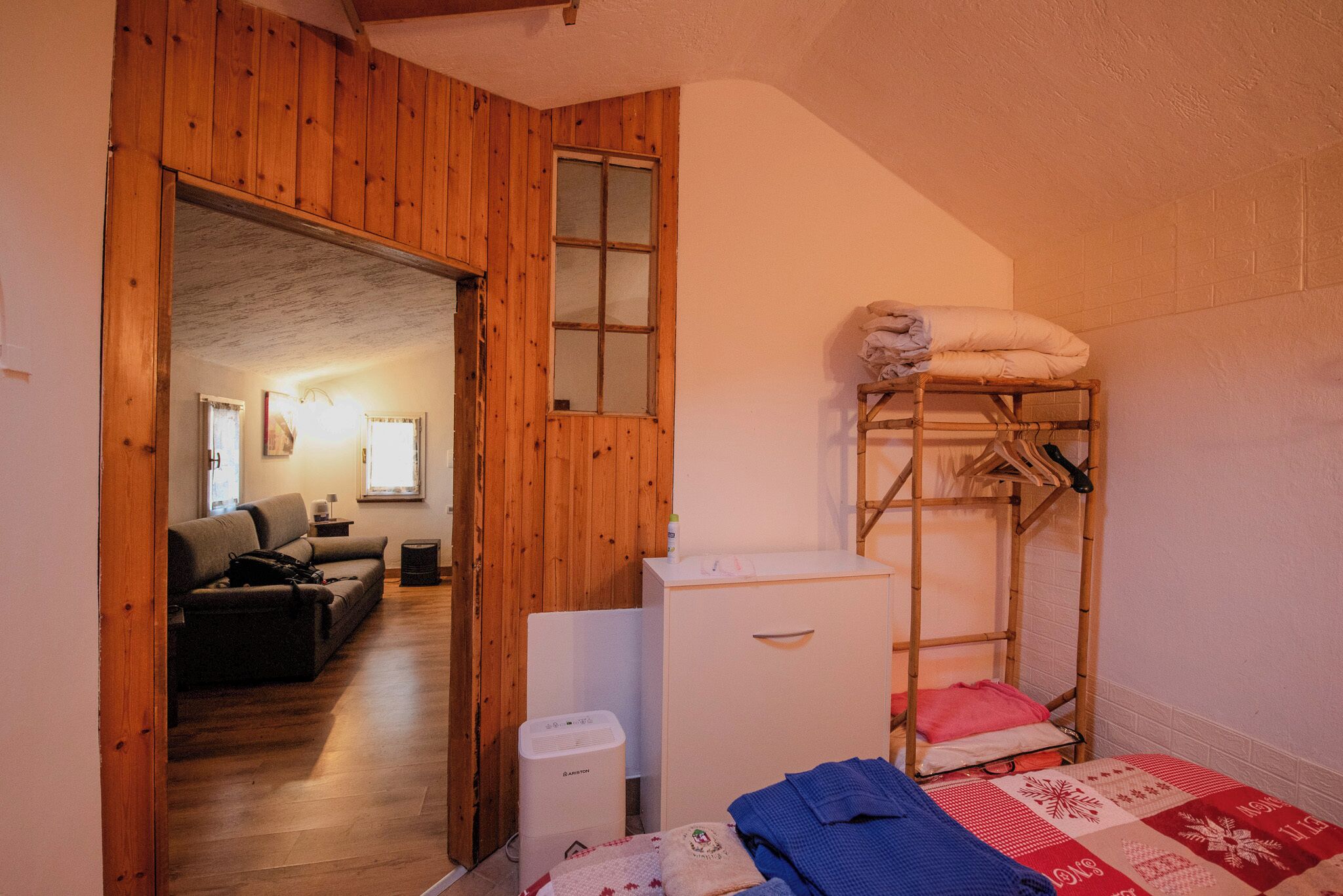 Habitación pequeña con una litera, un armario blanco y un sofá al fondo.