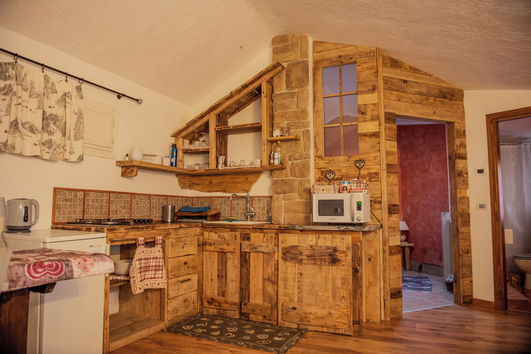 Una cocina rústica con armarios de madera, un zócalo de piedra y un microondas.